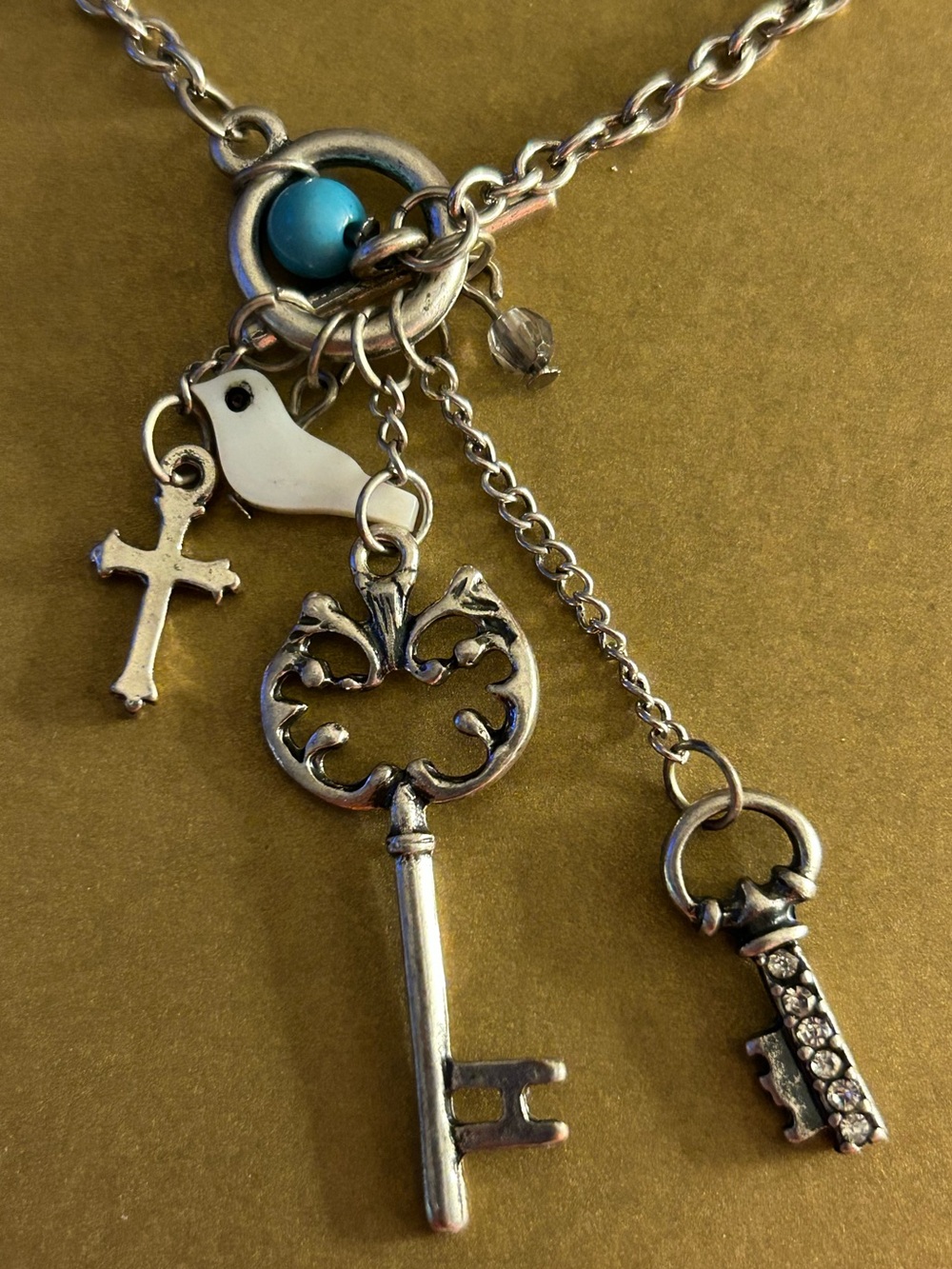NWOT charm Necklace Mother of Pearl Bird, keys, crystals, cross, blue stone